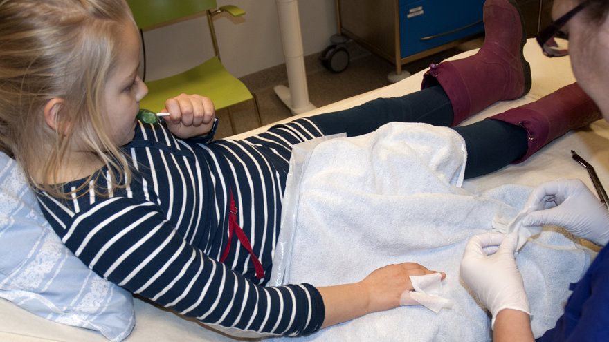 Ett barn med kompressser mellan fingrarna