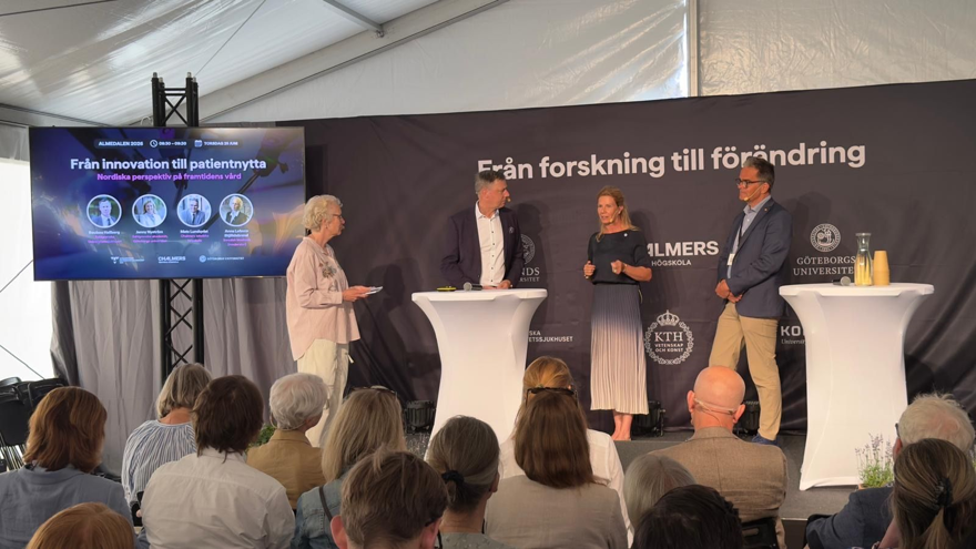 Fyra personer på scen för en diskussion inför publik.