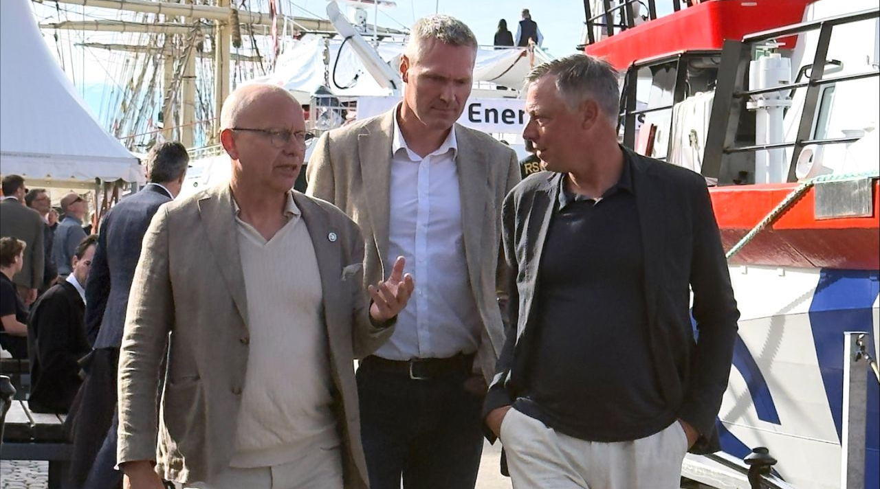Tre personer promenerar på en brygga.