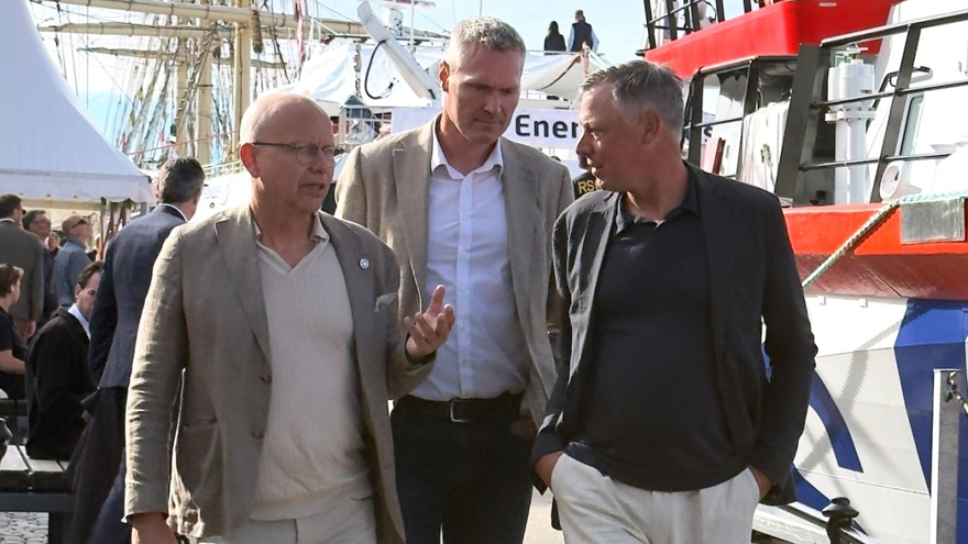 Tre personer promenerar på en brygga.