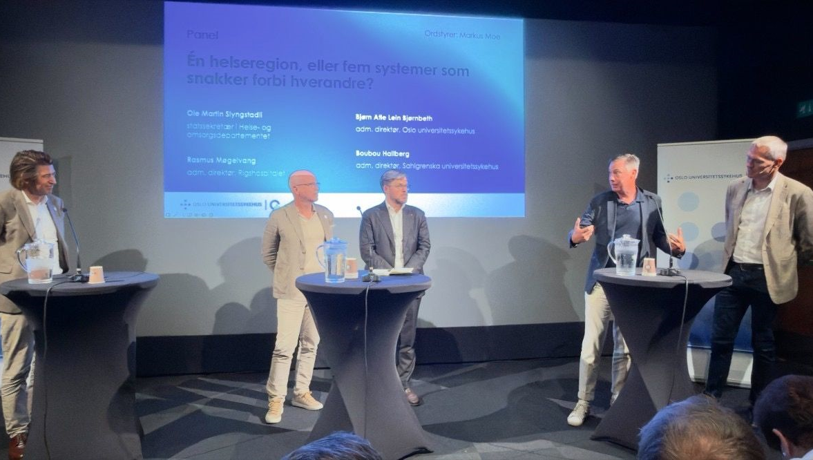 Fem personer i paneldiskussion på scen.