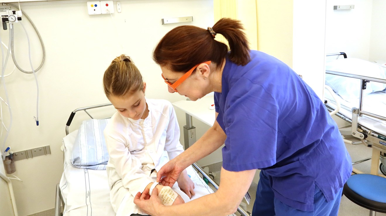 En sjuksköterska sätter ett namnband runt handleden på ett barn