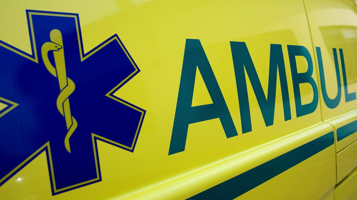 Ena sidan av en gul ambulans, med ambulansens logotyp synlig