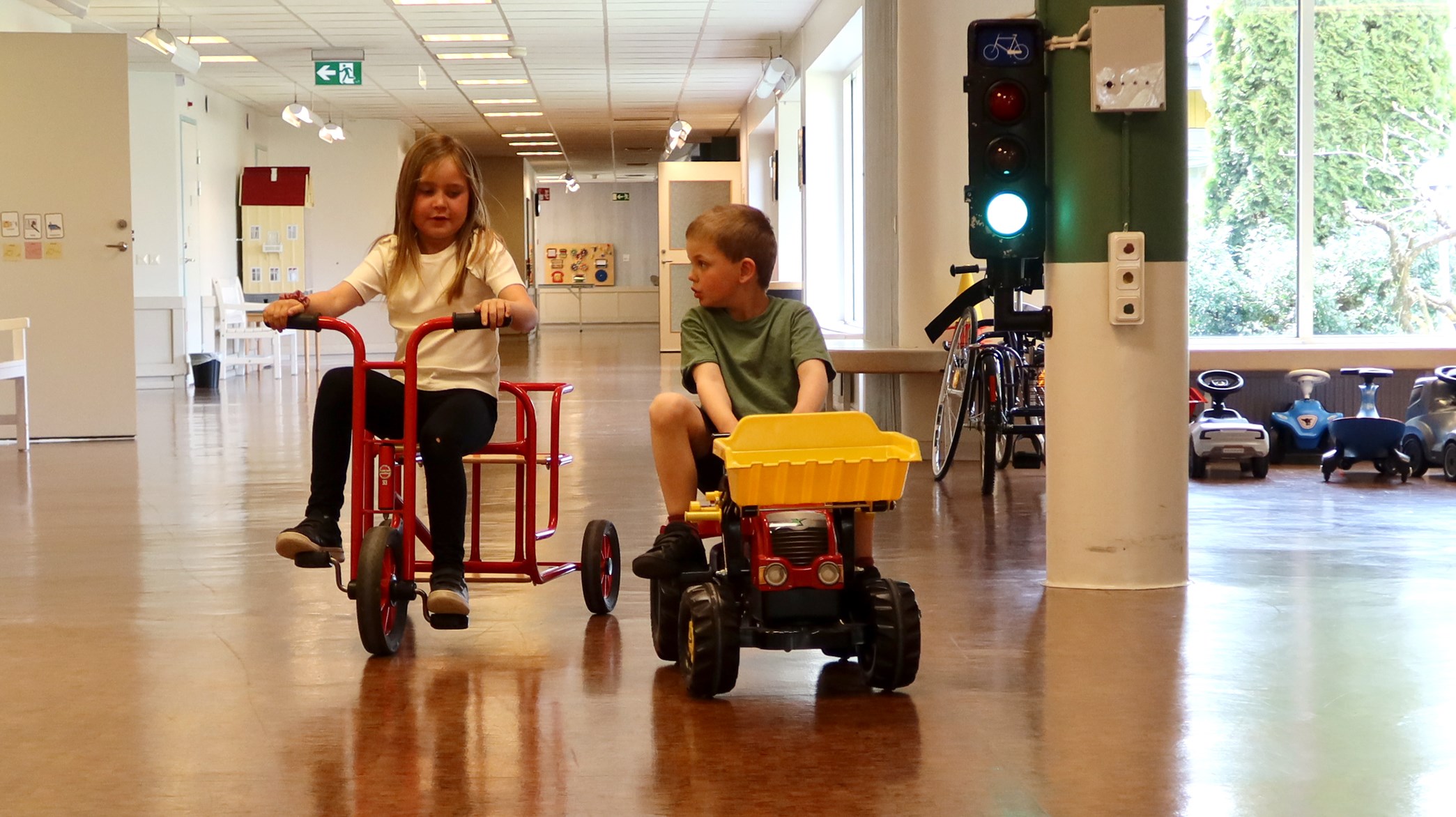Två barn cyklar och åker traktor