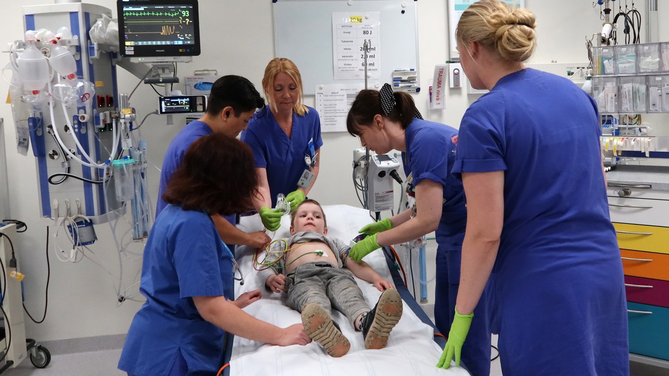 Många personer runt ett barn på en brits