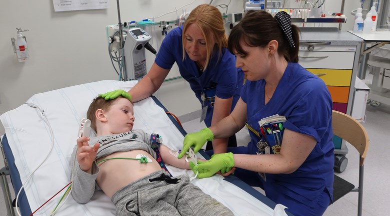 Två sjuksköterskor tar prov i armen på ett barn