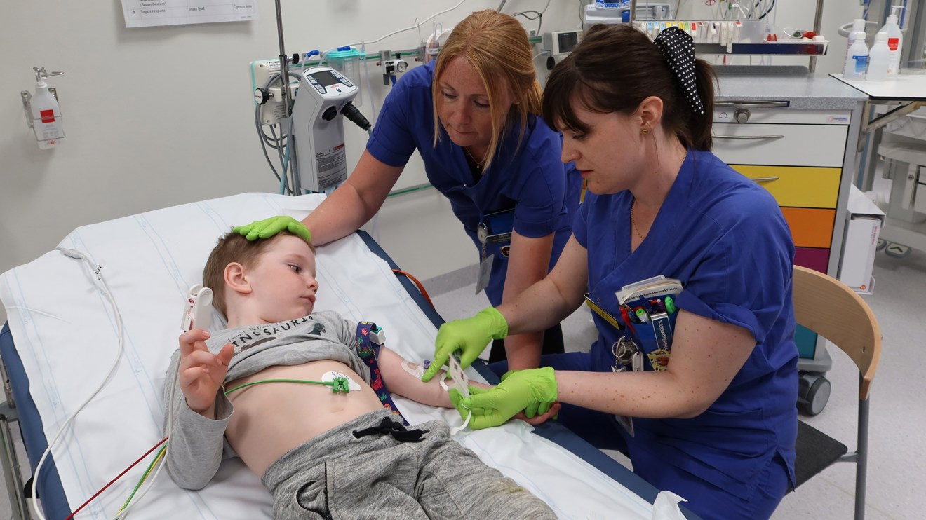 Två sjuksköterskor tar prov i armen på ett barn