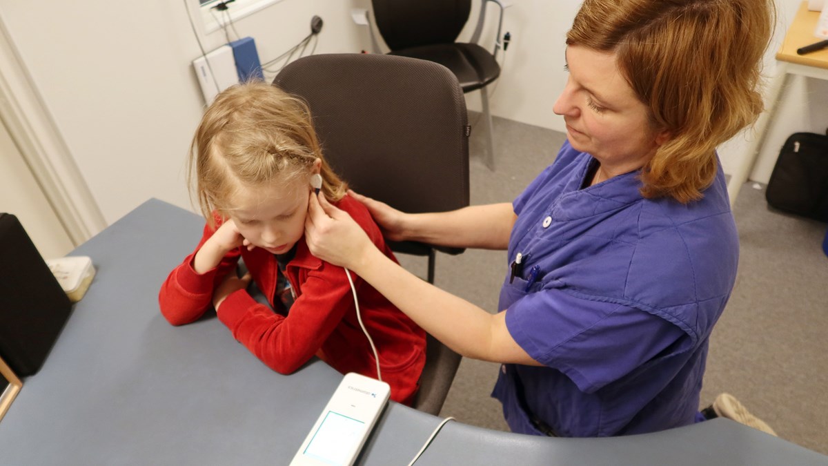 Ett barn med en liten apparat i örat