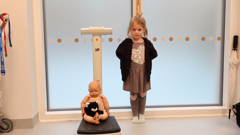 Ett barn och en docka väger sig och mäter sig