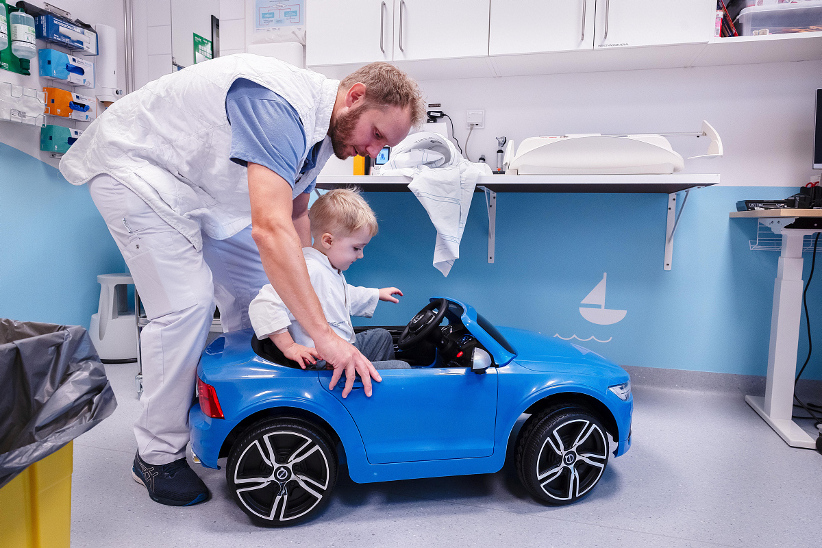 A doctor helping a child get in to a toy car.