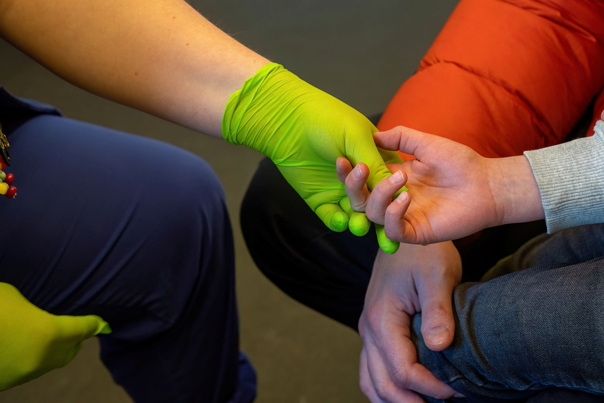 A gloved hand holding a childs hand.