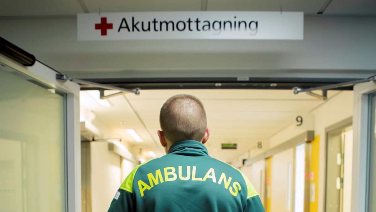 Person med tröja där det står ambulans, står under akutmottagning-skylt
