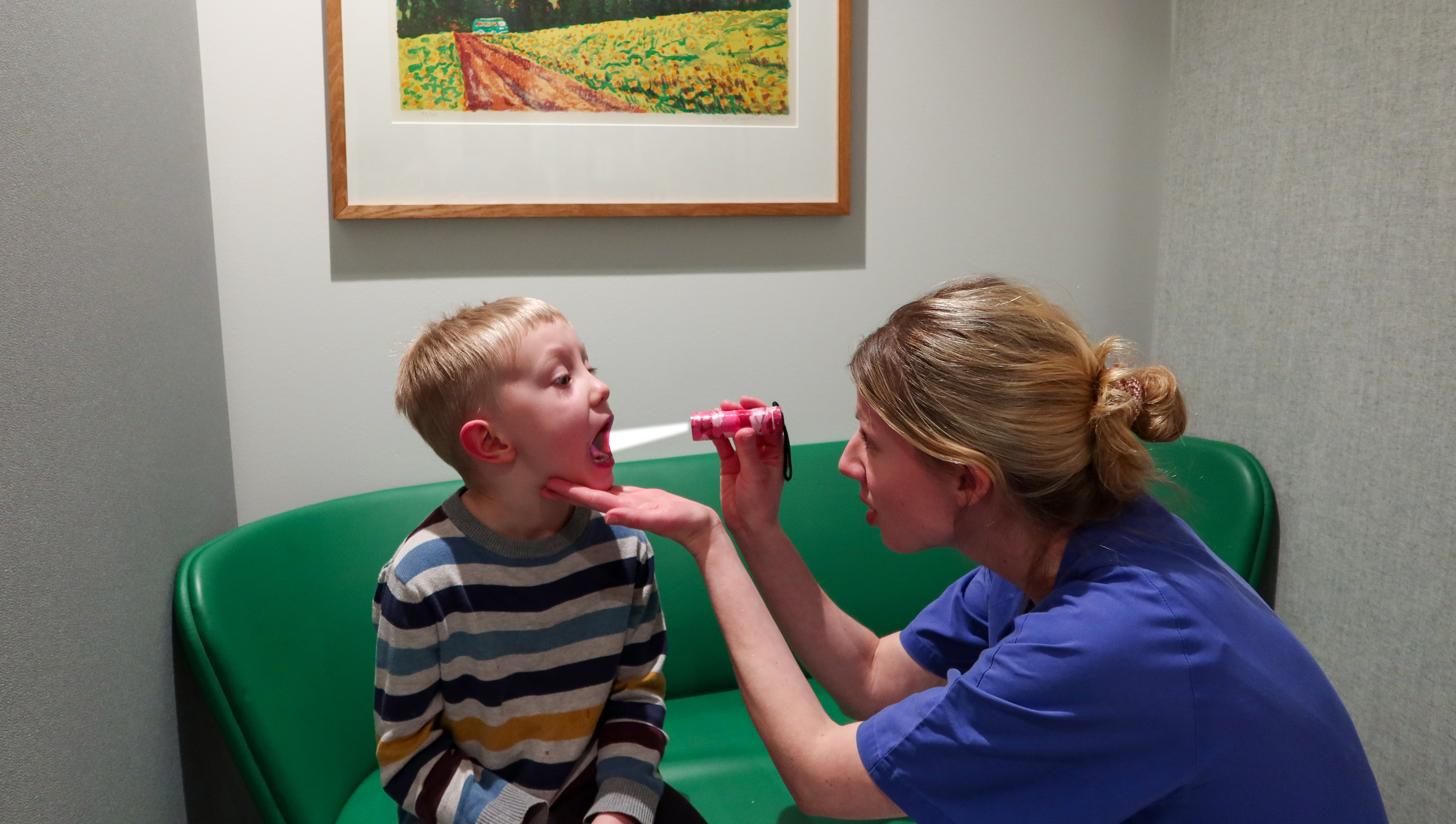 En doktor lyser i munnen på ett barn