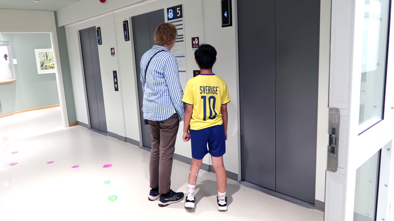 Ett barn och en mamma utanför hissen